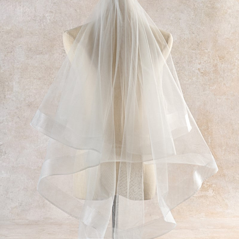 White tulle veil on a mannequin against a neutral background