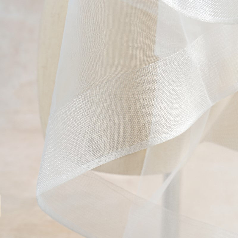 Close-up of sheer white horsehair trim with a soft texture on a light pink background