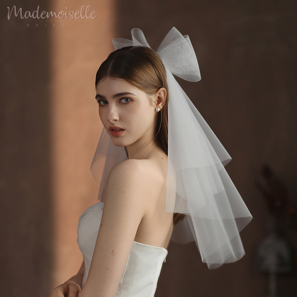 A stunning bride in a flowing wedding veil, featuring a chic bow, radiating elegance and romance on her special day.