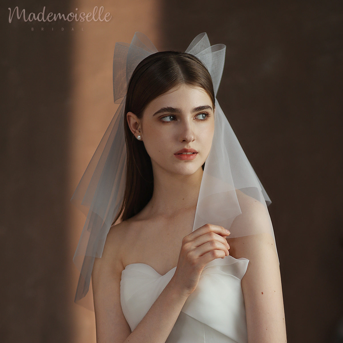 A lovely woman in a wedding veil, elegantly holding her hair, capturing the essence of bridal charm and grace.