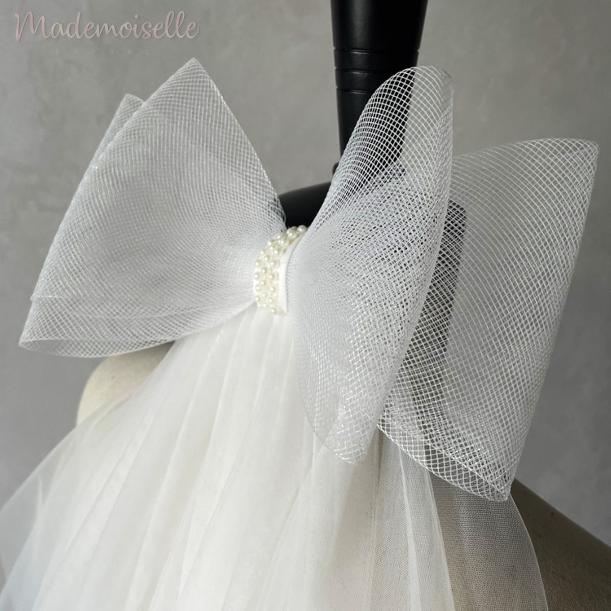 A delicate white wedding veil adorned with a charming bow, epitomizing elegance and romance for the perfect bridal look.