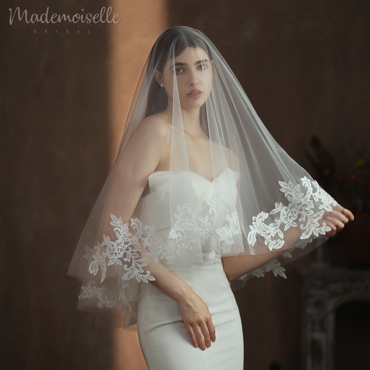 A bride adorned in a delicate white lace wedding veil, exuding elegance and timeless beauty on her special day.