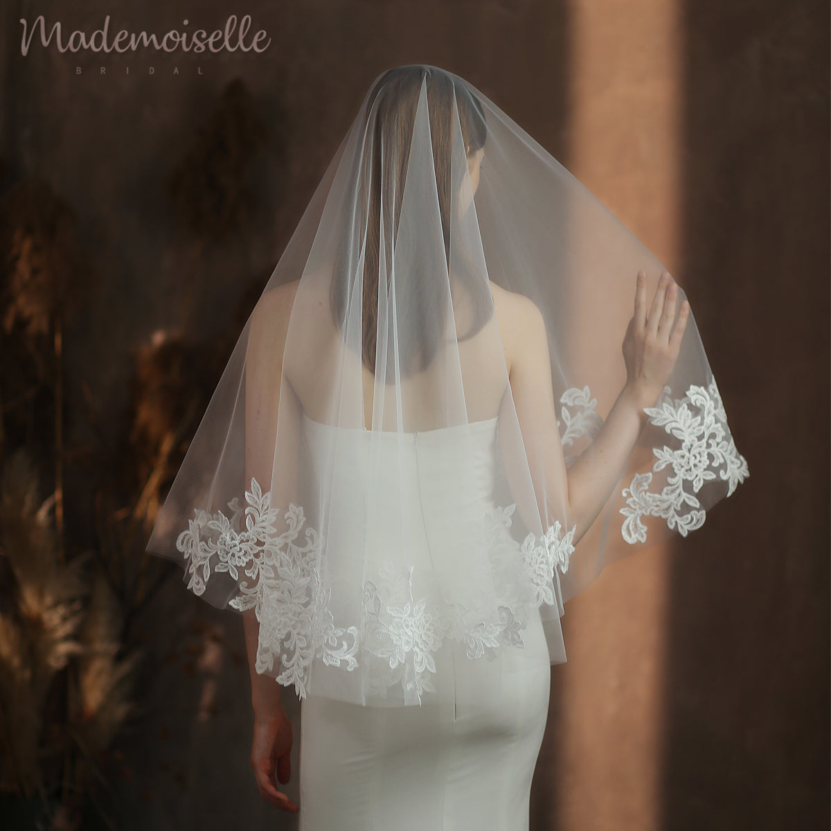 A stunning bride in a delicate white lace veil, captured from the back, exuding elegance and grace on her special day.