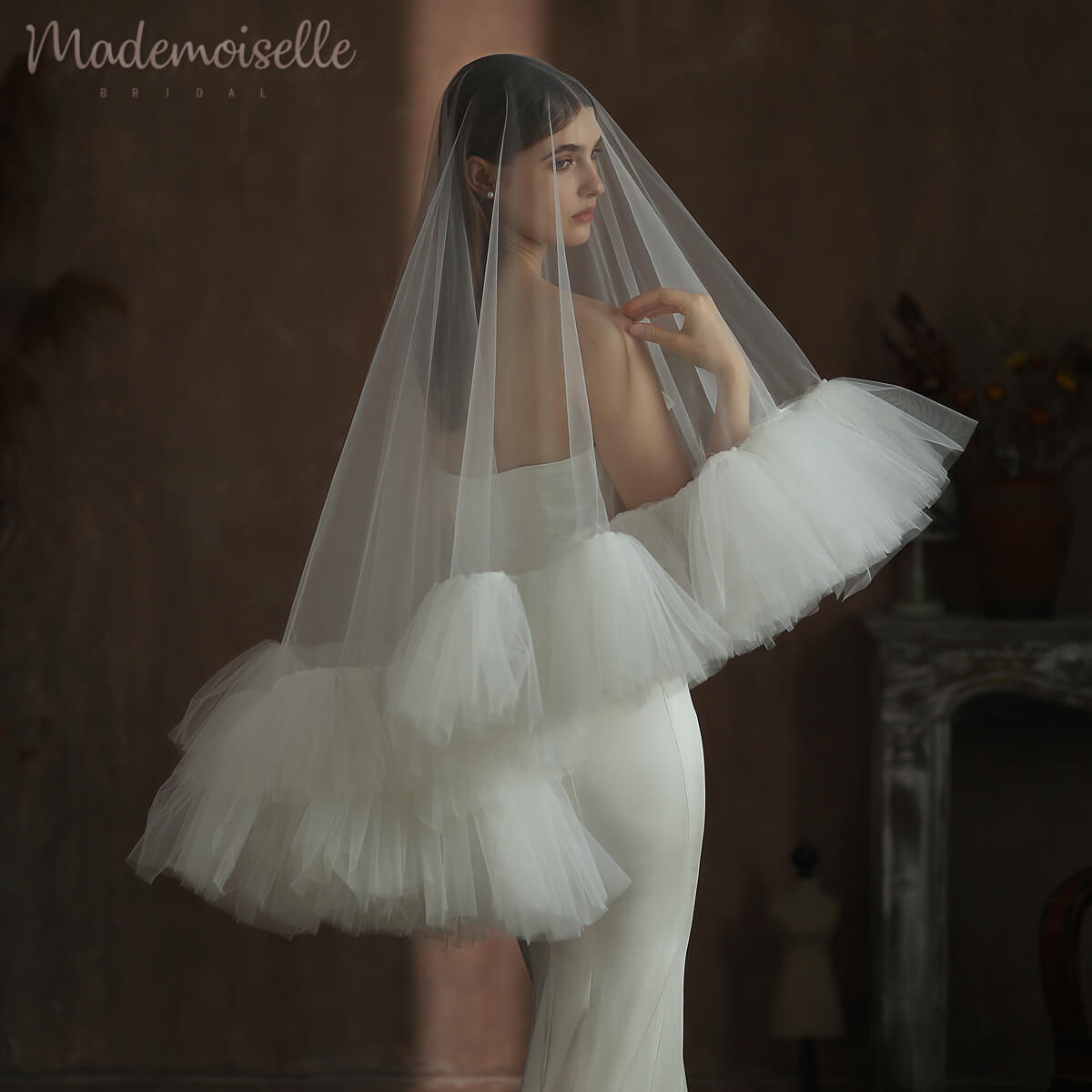 A stunning bride in a white tulle veil with a ruffle edge, showcasing a long train that enhances her enchanting wedding look.