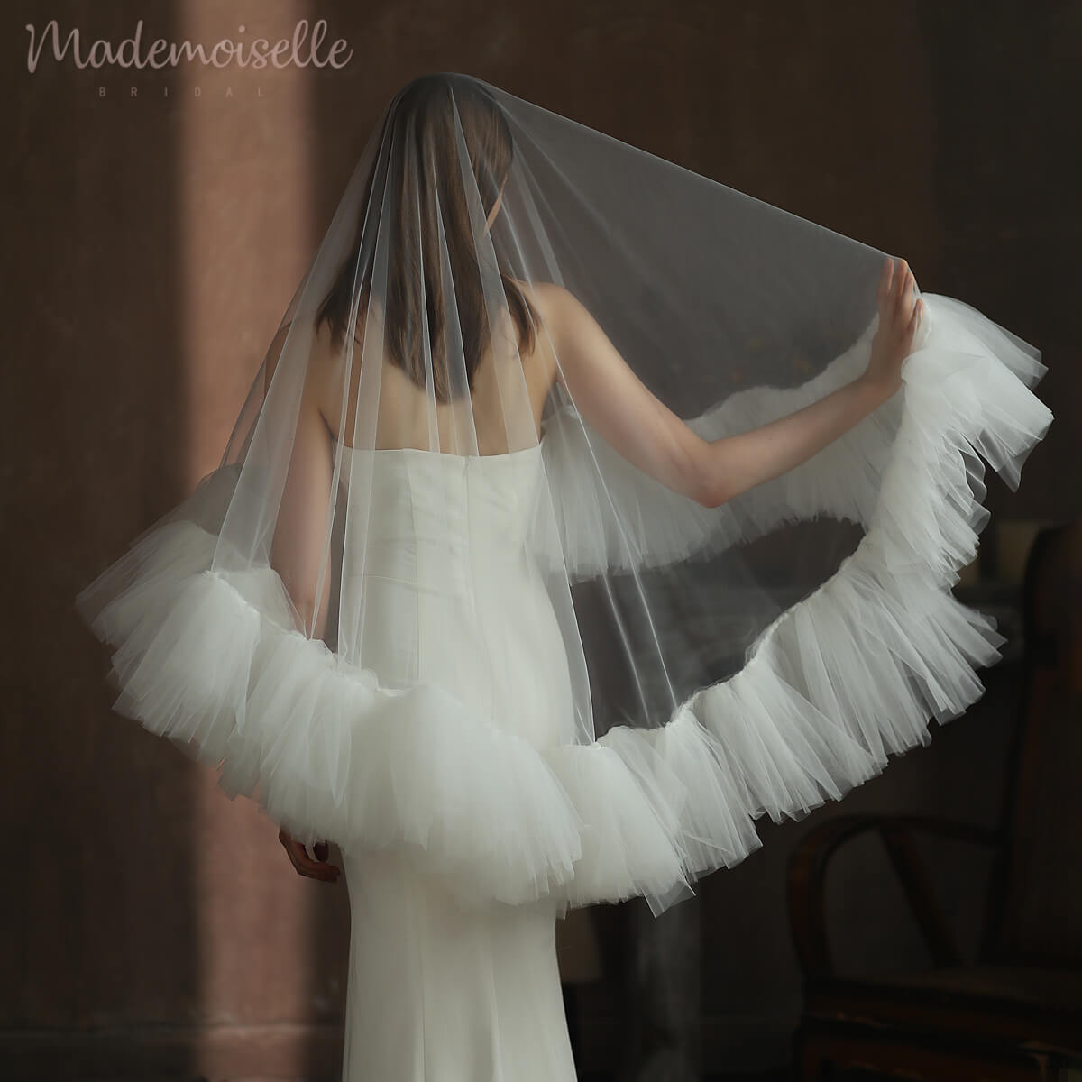 A stunning bride in a white tulle veil, elegantly framed with a ruffle edge, radiating grace and sophistication.