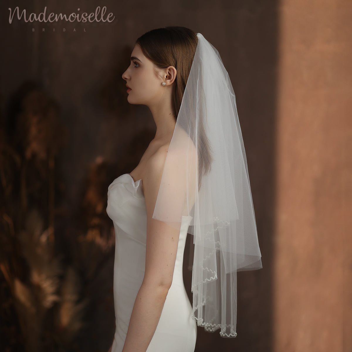 A bride adorned in a delicate wedding veil featuring a stunning beaded edge, radiating elegance and grace on her special day.