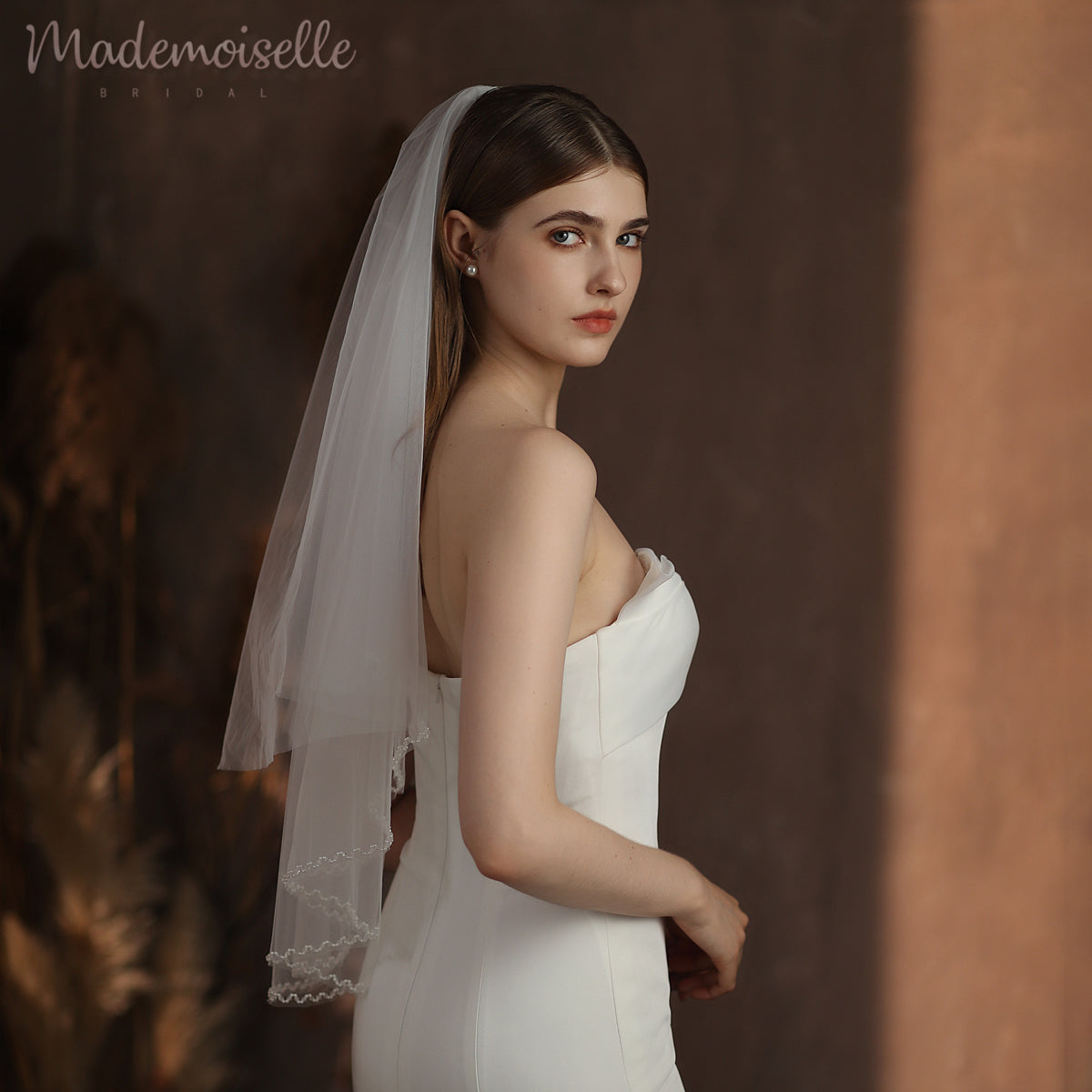 A beautiful bride dons a lightweight wedding veil with a beaded edge