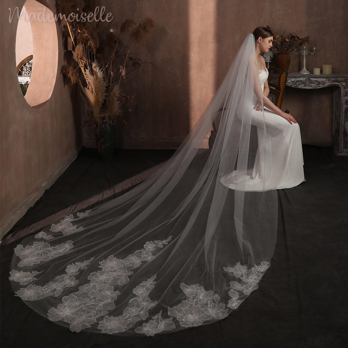 In a luxurious setting, a bride sits gracefully, her exquisite cathedral veil draping elegantly, capturing a moment of pure bliss.