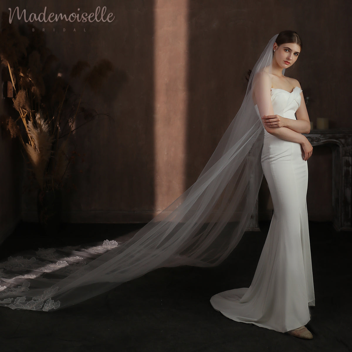 Captivating bride in a long cathedral veil poses for the camera, exuding timeless elegance and charm.