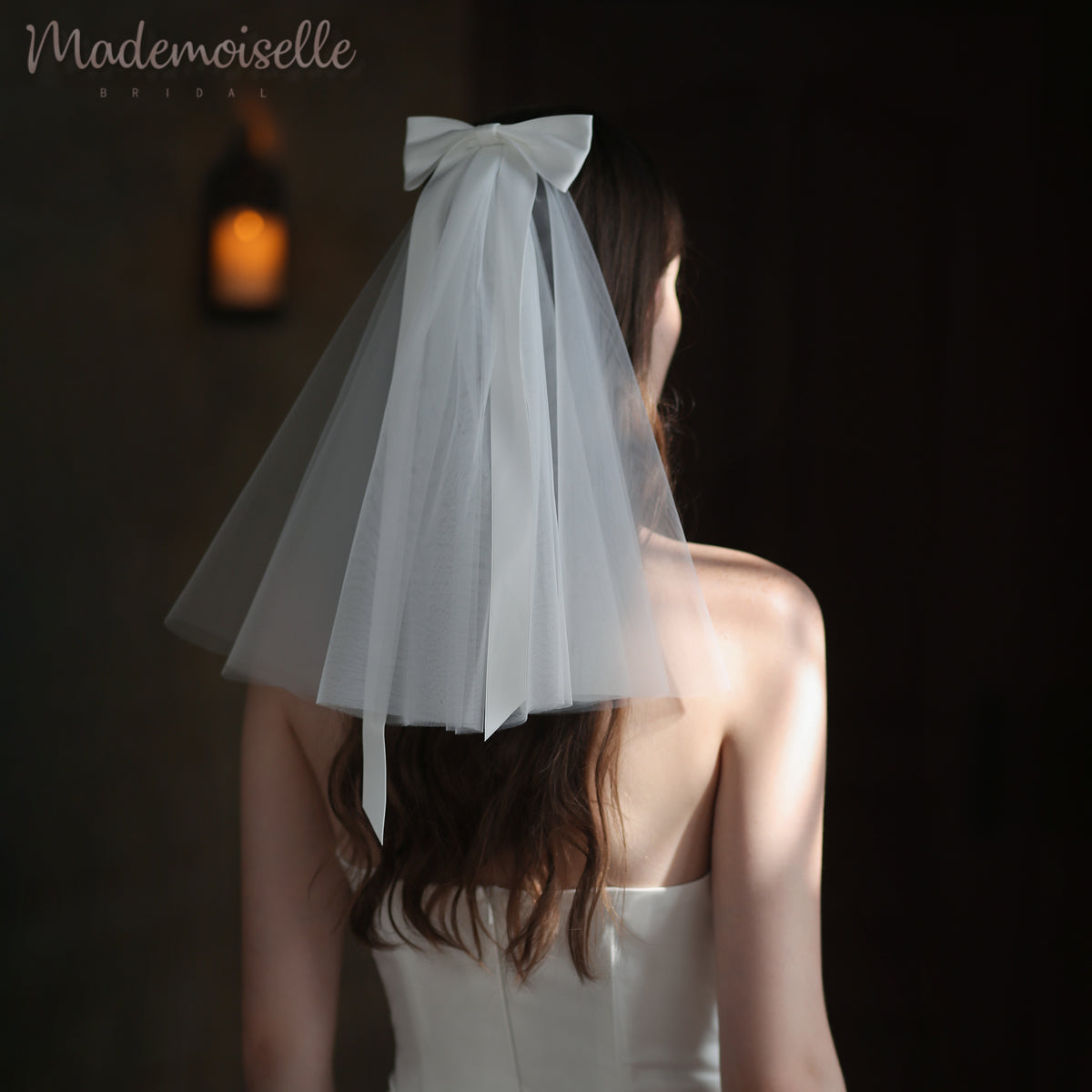 A bride's back, elegantly showcased with a flowing veil with a satin bow, embodying the enchanting allure of a wedding day.