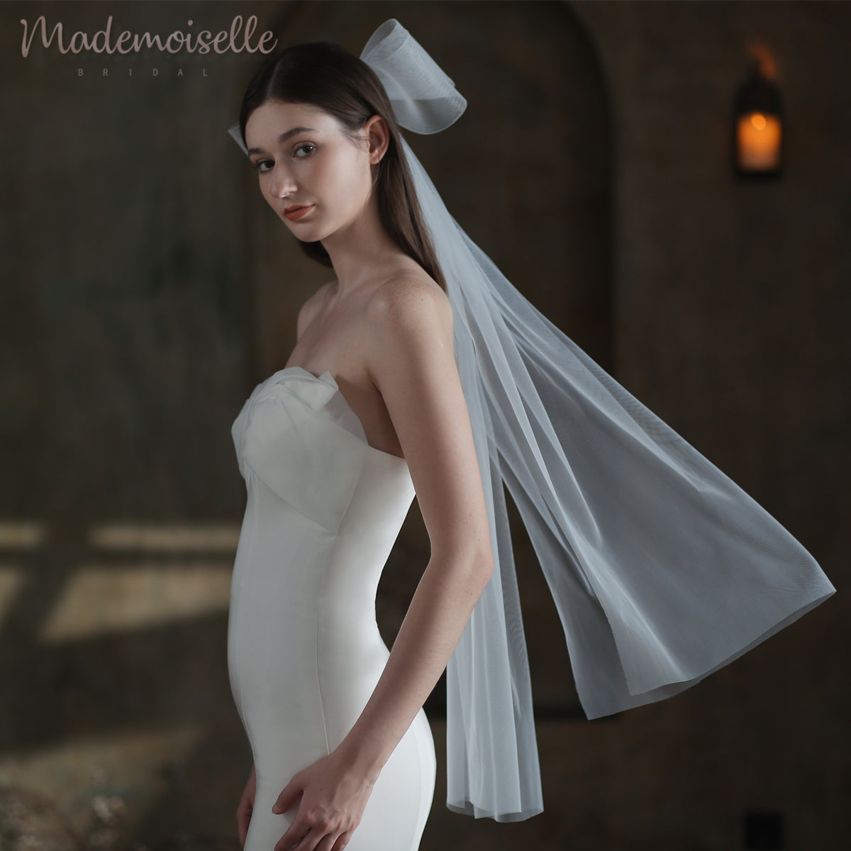 The bride, adorned in a stunning white gown and ethereal veil with an oversized bow, exudes timeless elegance and joy on her wedding day.