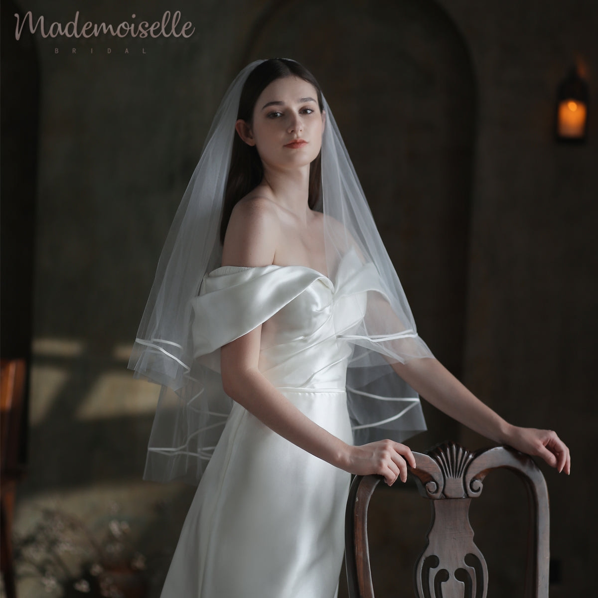 A stunning bride in a wedding dress, adorned with a ribbon-trimmed veil, elegantly posing for a cherished photograph.