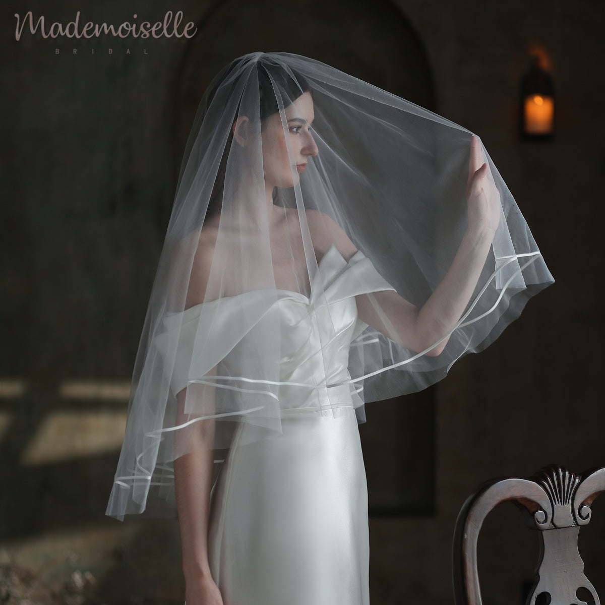 A radiant bride in a luxurious wedding dress, elegantly topped with a soft, flowing veil featuring ribbon trim detail