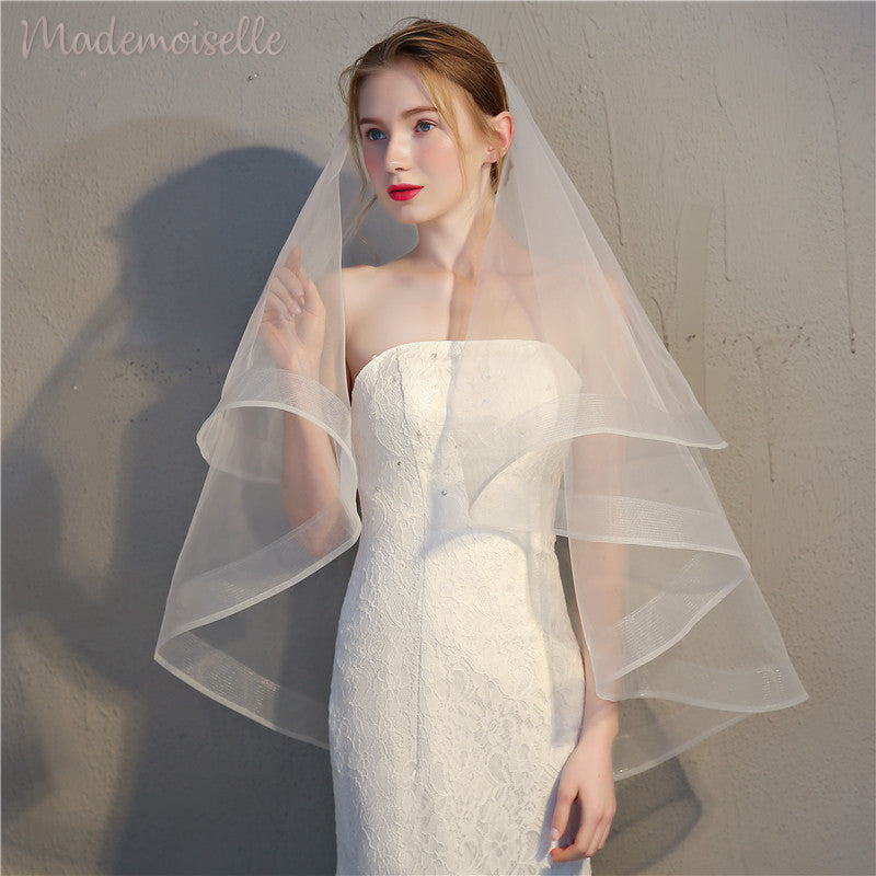 A bride in a delicate wedding veil, holding her hand gracefully, capturing a moment of love and celebration.