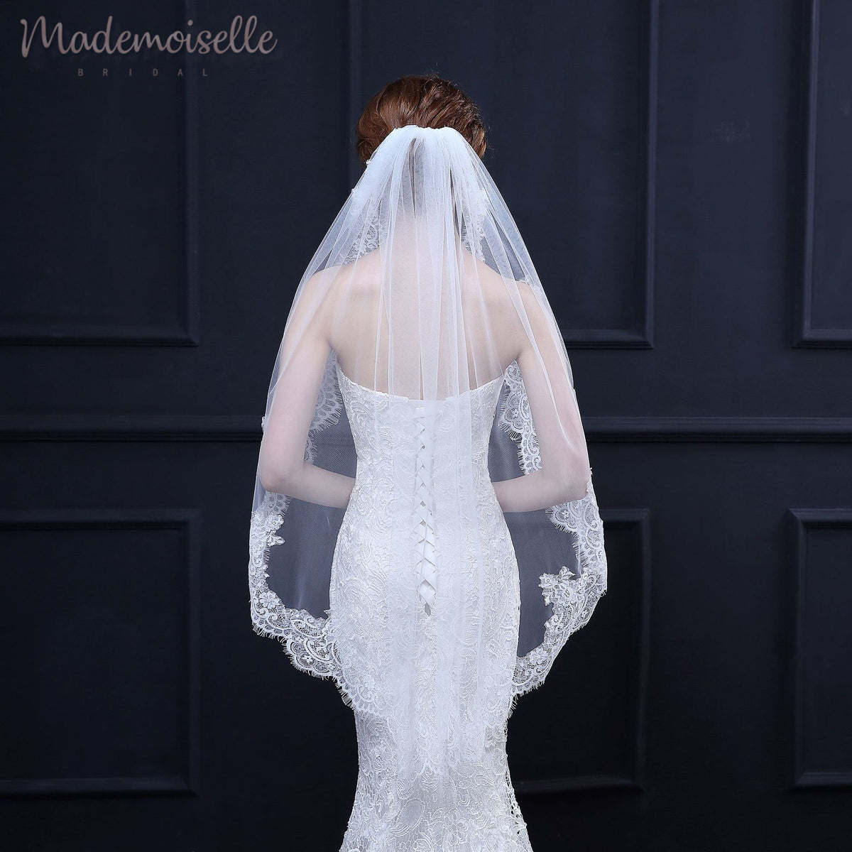 A bride's silhouette from the back, showcasing a beautiful wedding veil that enhances her enchanting appearance.