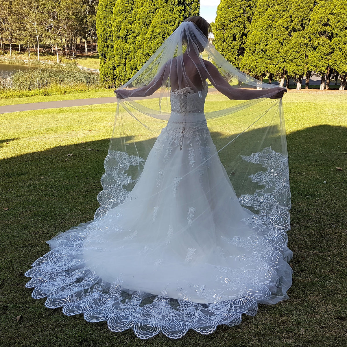 A bride in a stunning wedding gown stands on vibrant grass, capturing a moment of happiness and celebration.