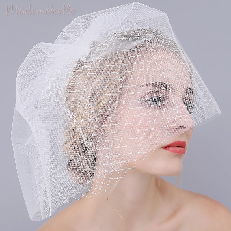 Model wearing a white birdcage wedding veil