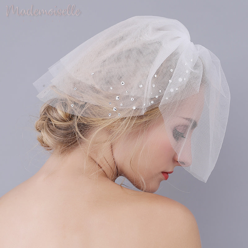 Model wearing a white birdcage wedding veil with crystals
