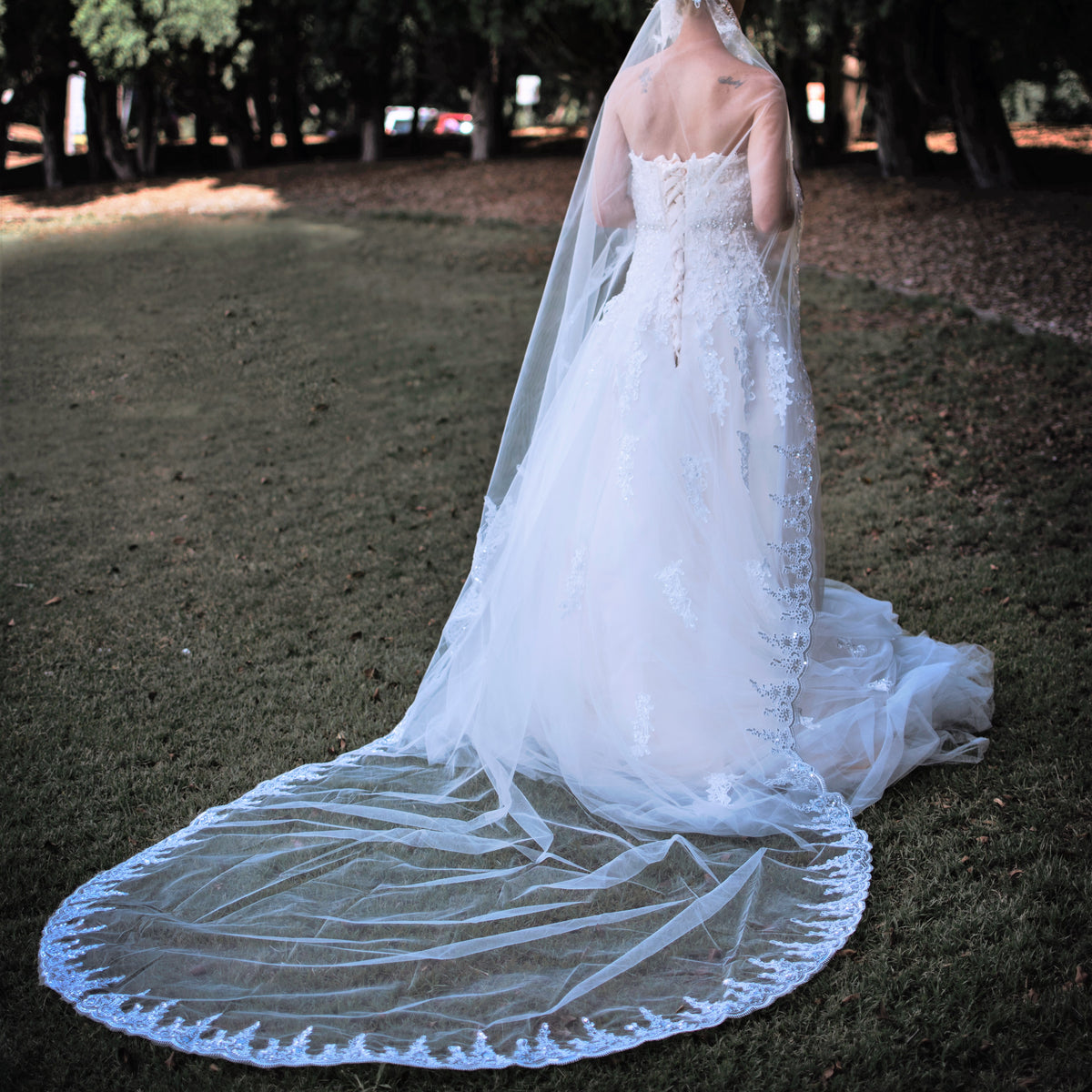 A bride in a lovely wedding dress stands in the grass, capturing a moment of happiness and serenity on her wedding day.