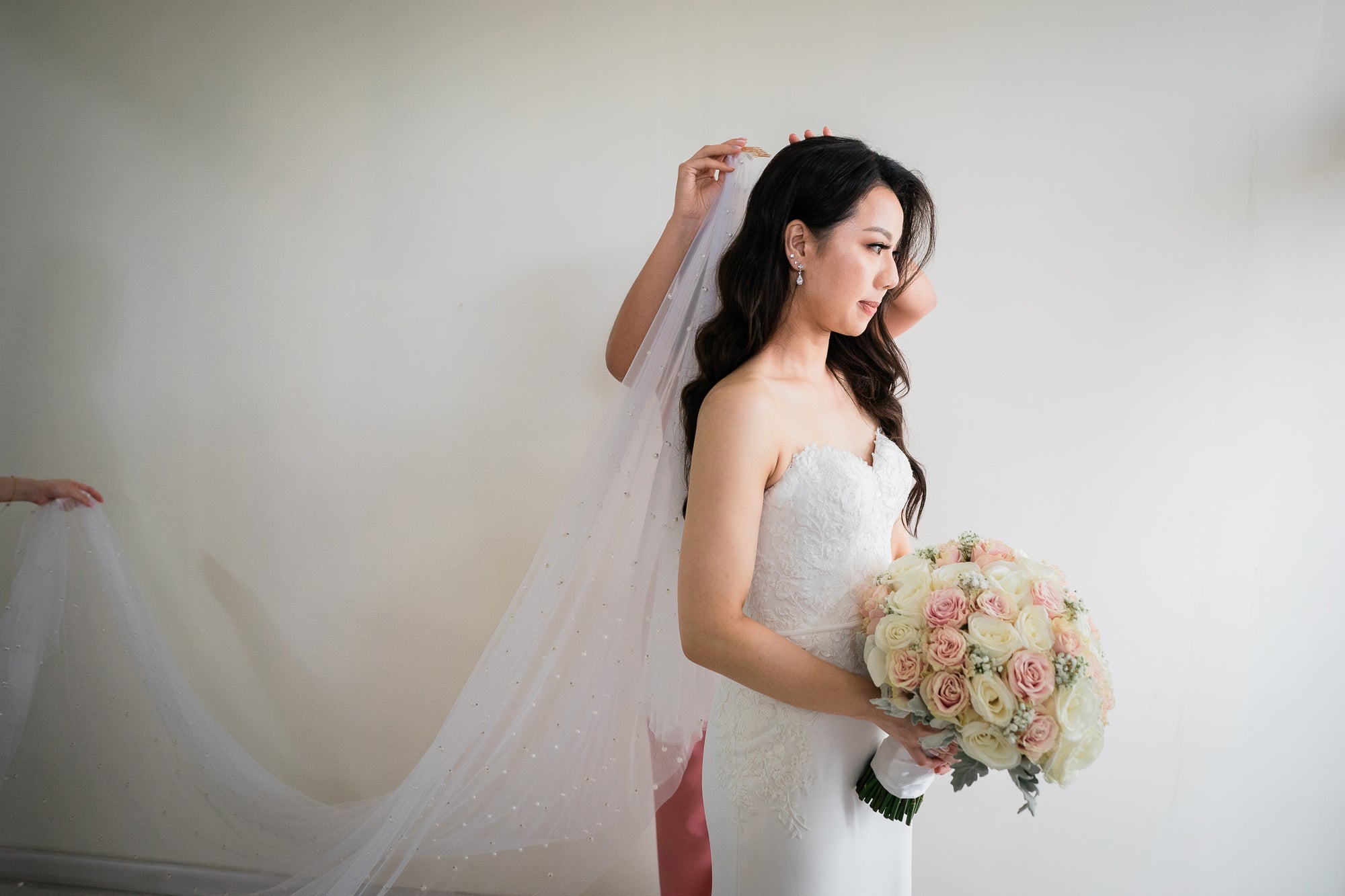Bride wearing the christella pearl wedding veil while holding the bouquet