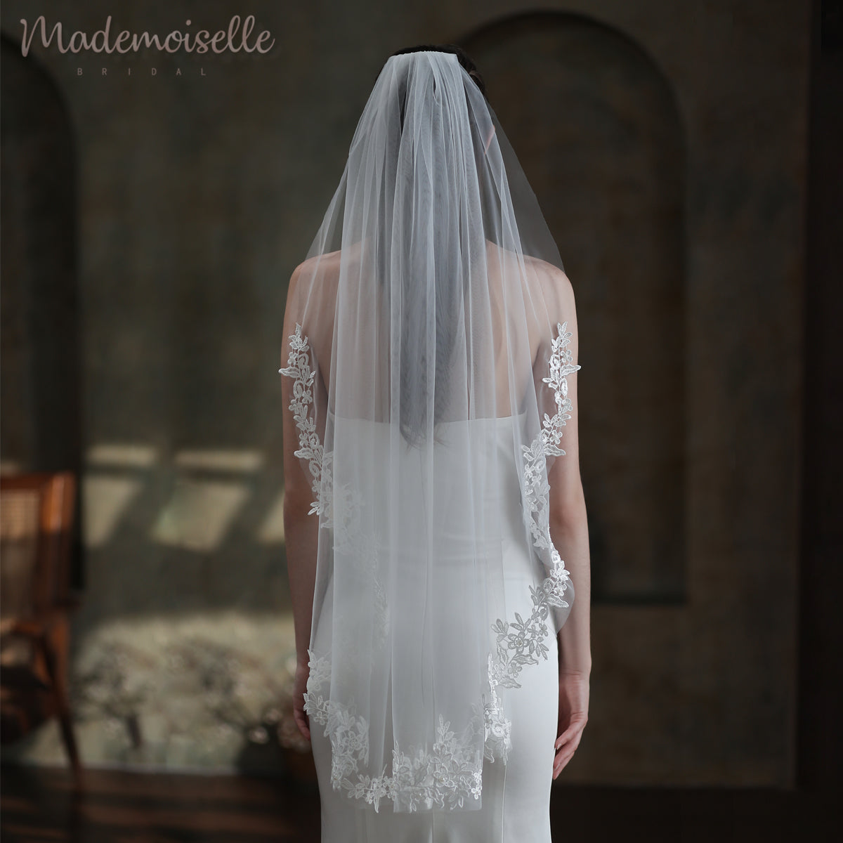 A bride&#39;s enchanting silhouette from behind, featuring a luxurious wedding veil with a beautiful lace trim that enhances her ethereal charm.