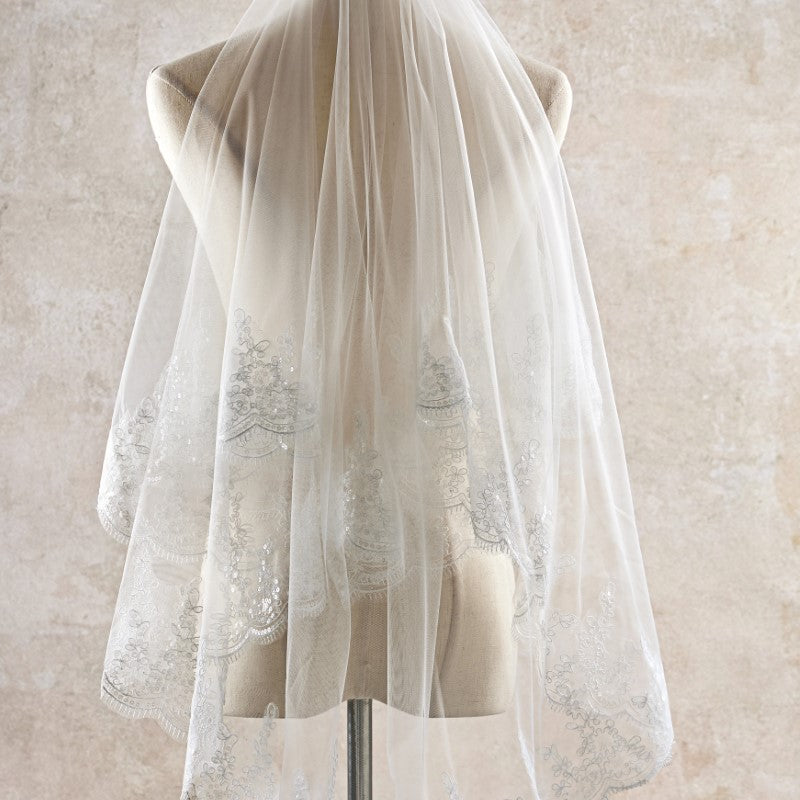 White lace veil on a mannequin against a beige background
