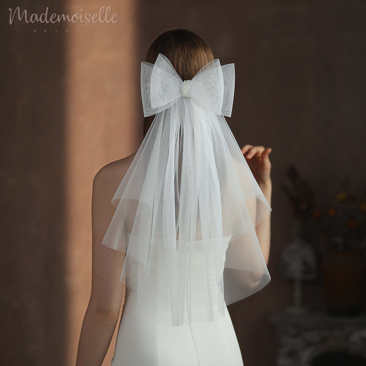A bride&#39;s elegant back adorned with a delicate veil and a charming bow, radiating grace and sophistication.