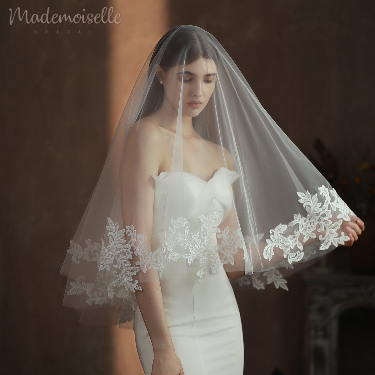 The bride&#39;s exquisite white wedding veil, intricately designed with lace, enhances her timeless beauty and sophistication.