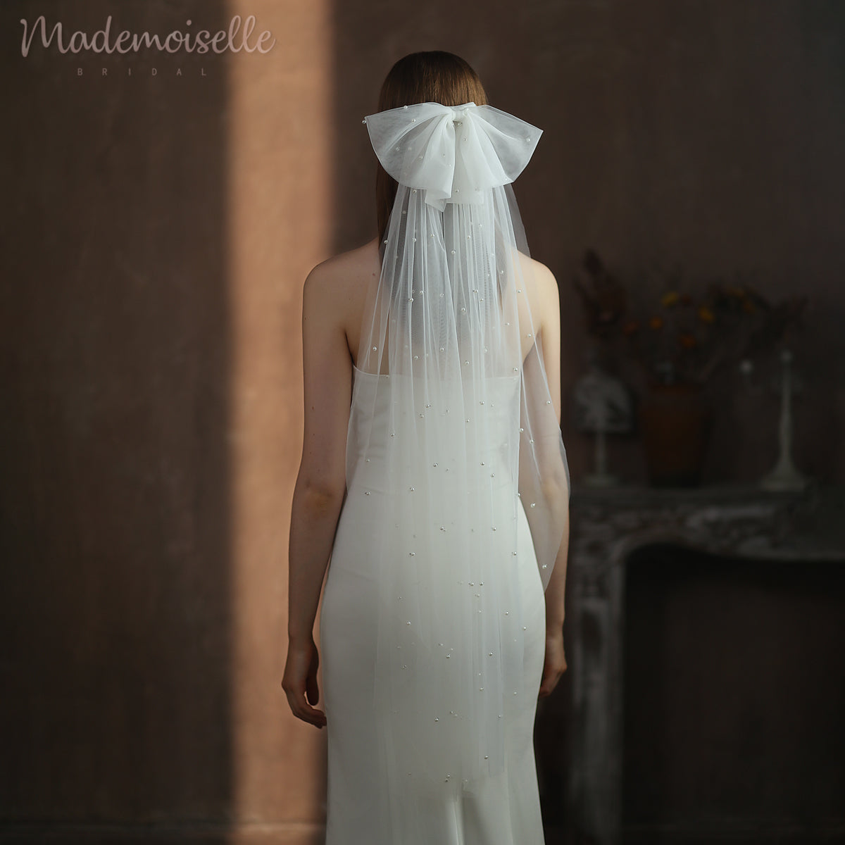 The enchanting back of a bride, gracefully draped in a flowing pearl veil with a bow, symbolizing love and elegance on her wedding day.