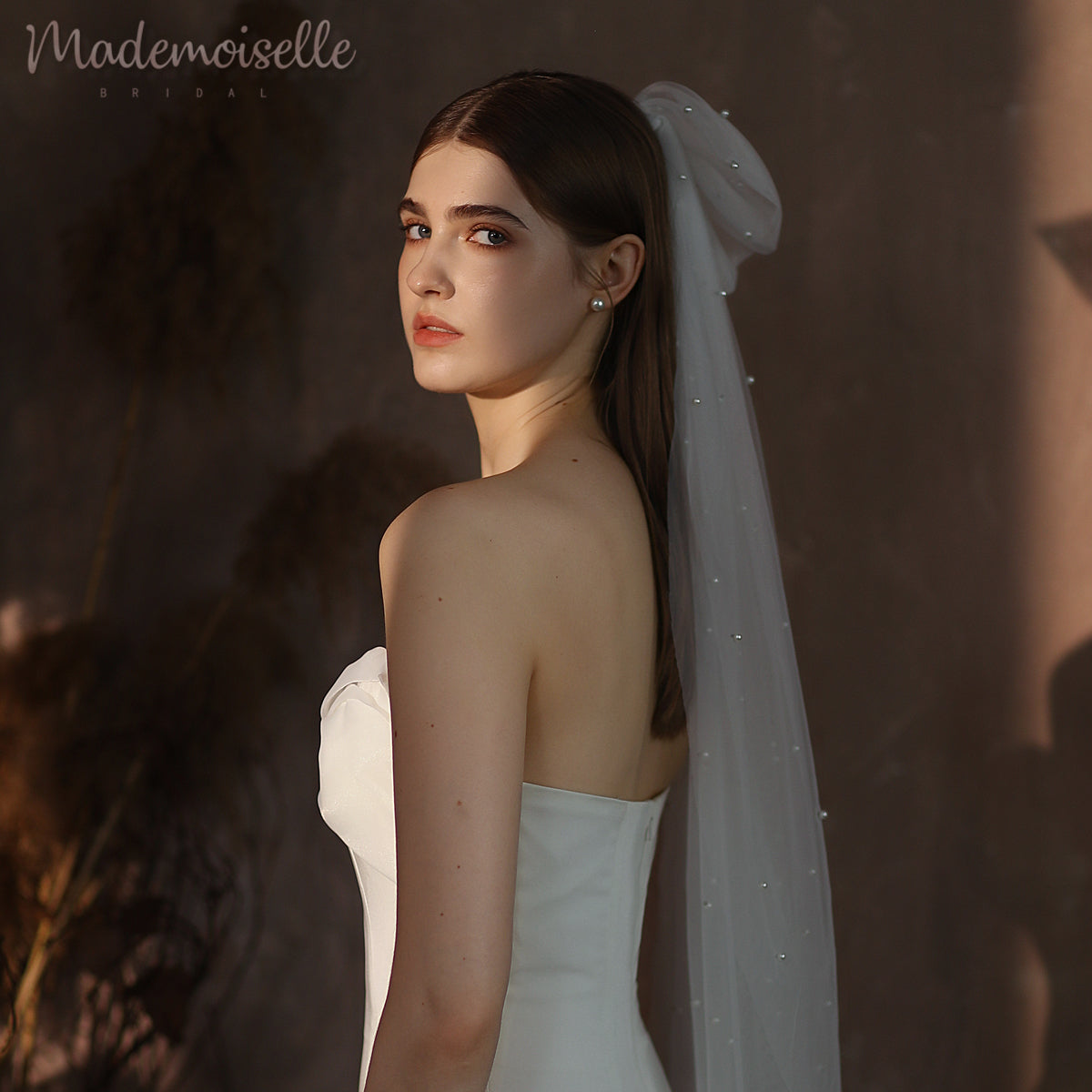 A radiant woman in a flowing white dress, adorned with an elegant pearl wedding veil, embodies grace and beauty on her special day.