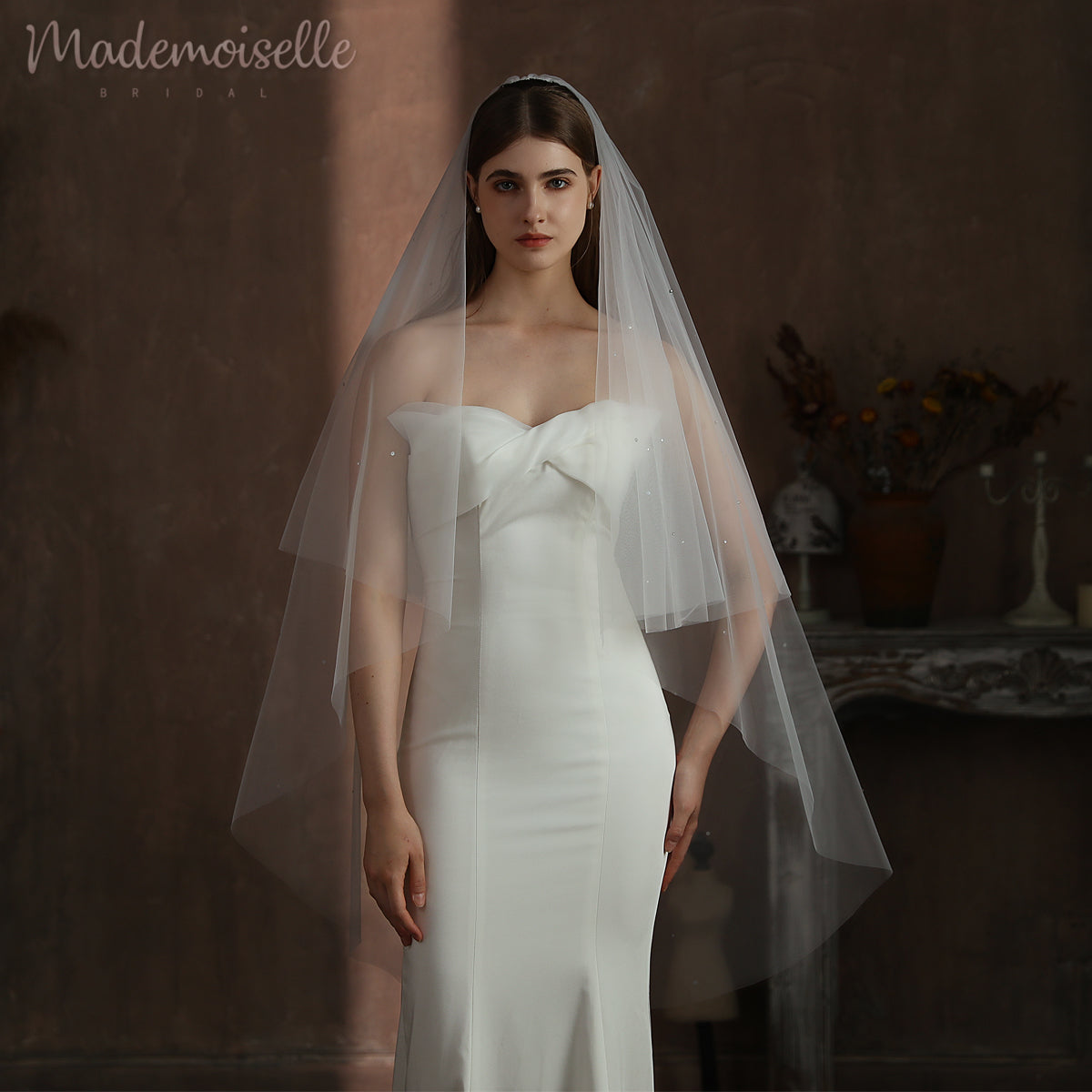 Dressed in an exquisite white wedding gown, the bride&#39;s veil cascades elegantly, highlighting her enchanting presence on this special day.