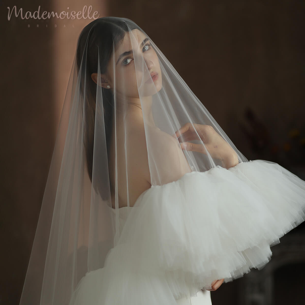 A bride adorned in a ruffled-edge wedding veil, elegantly cascading down her back, embodying timeless beauty and grace.