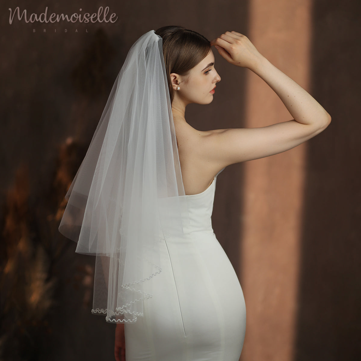Dressed in an exquisite white wedding gown, the bride captivates with her elegance, crowned by a soft, ethereal veil.