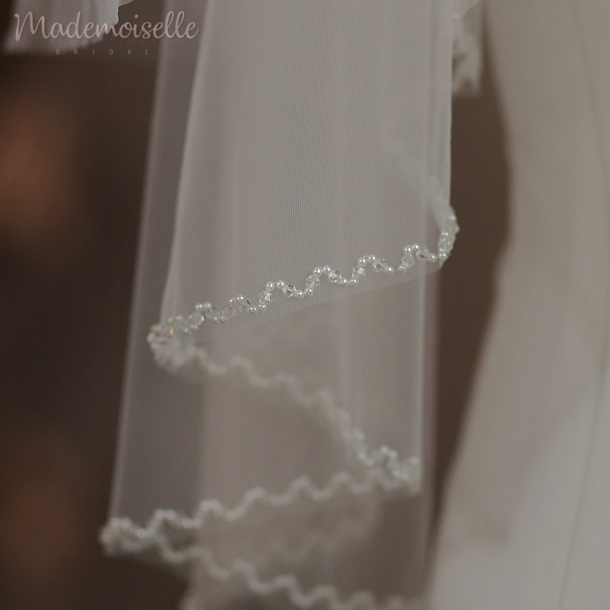 Dressed in an exquisite white wedding gown, the bride captivates with her elegance, crowned by a soft, ethereal veil.