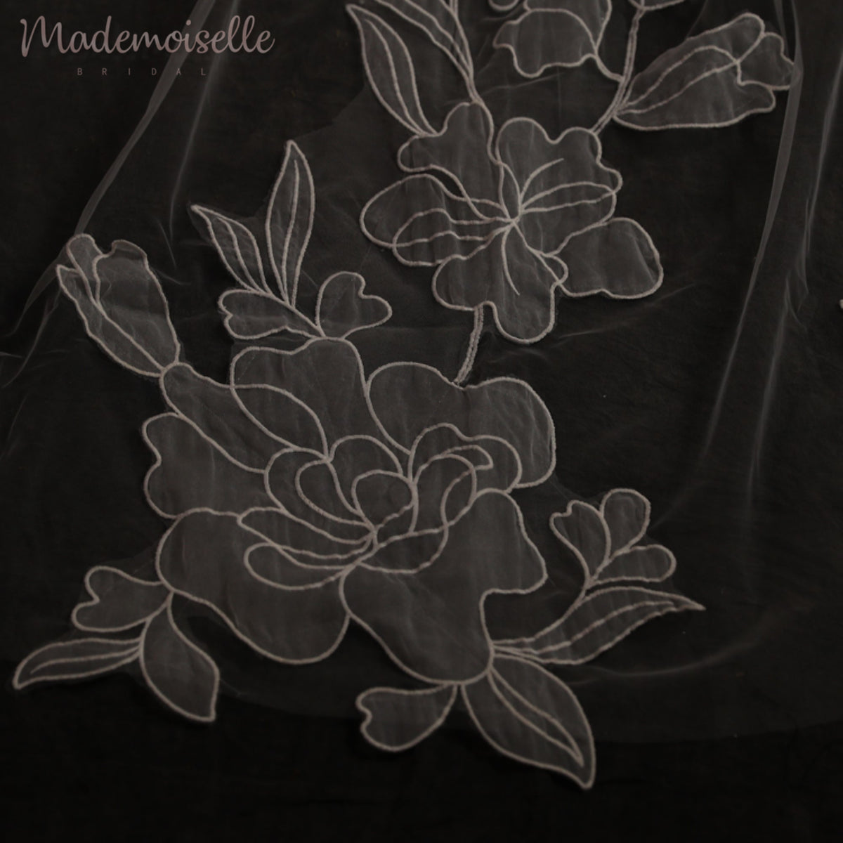 A refined close-up of delicate white floral lace, beautifully set against a striking black background.