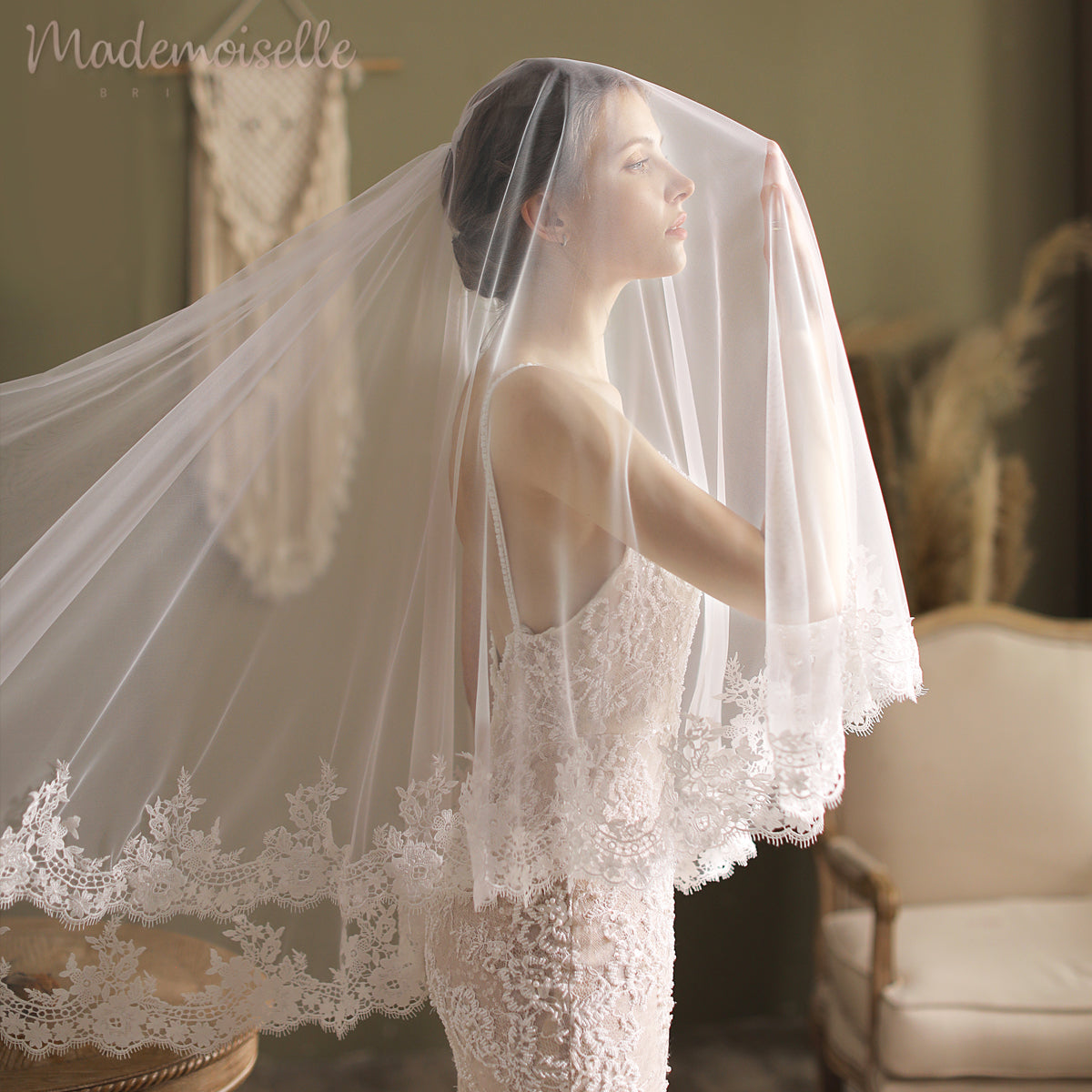 A bride adorned in a long lace veil, featuring an exquisite lace appliqué edge, radiates elegance and grace.