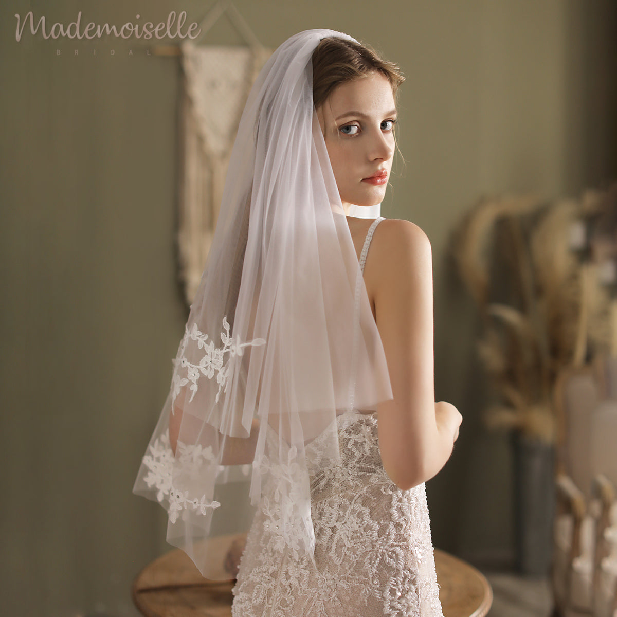 The bride&#39;s stunning white lace veil, embellished with a refined lace appliqué edge, enhances her timeless beauty.