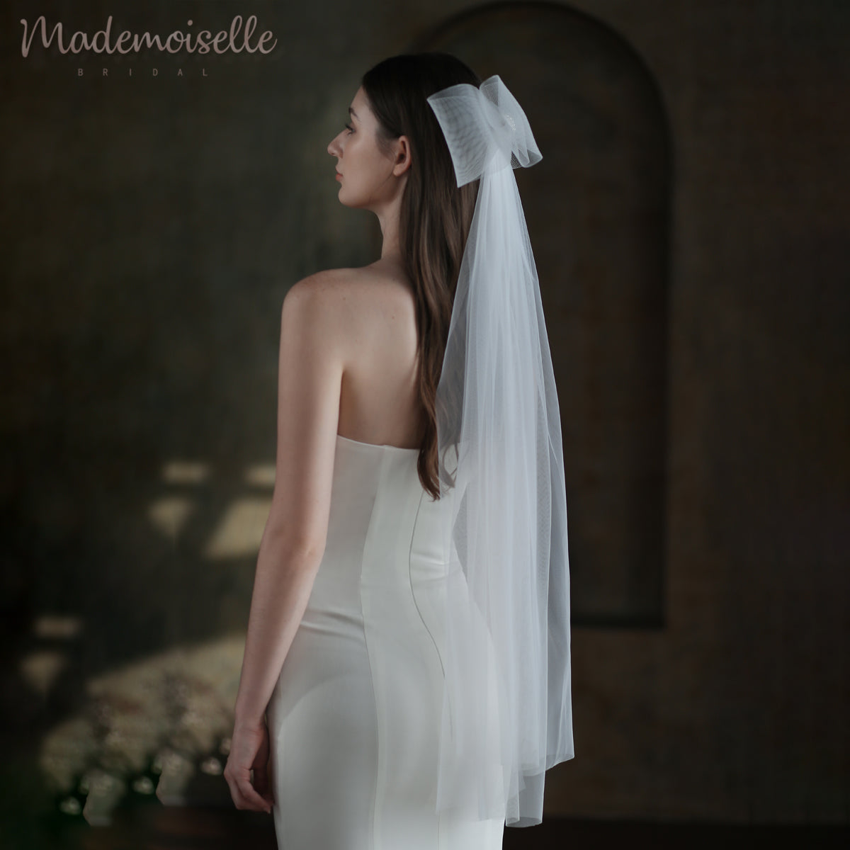 The bride, resplendent in her white wedding dress, captivates with a delicate veil with an oversized bow, symbolizing love and elegance on her special day.