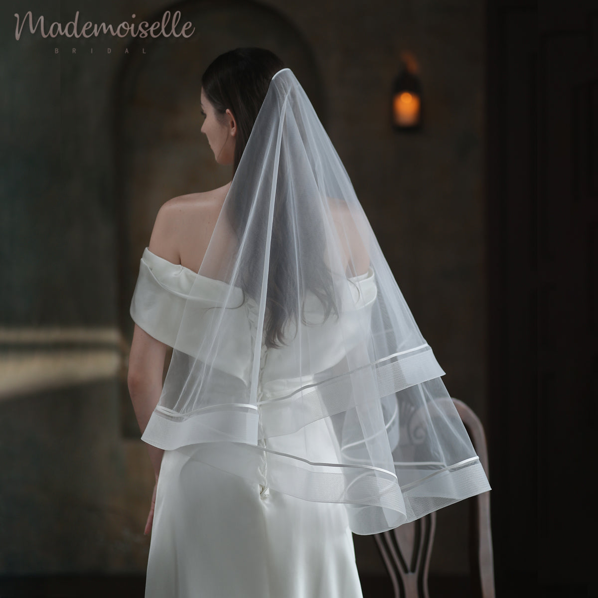 A bride adorned in a delicate white wedding veil, elegantly finished with exquisite horsehair trim, radiates timeless beauty.