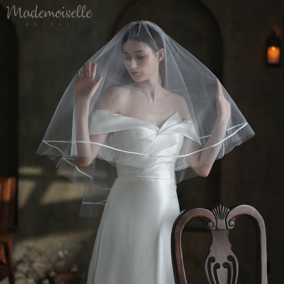 A bride in a luxurious wedding veil featuring delicate ribbon trim poses for a captivating photograph, exuding grace.