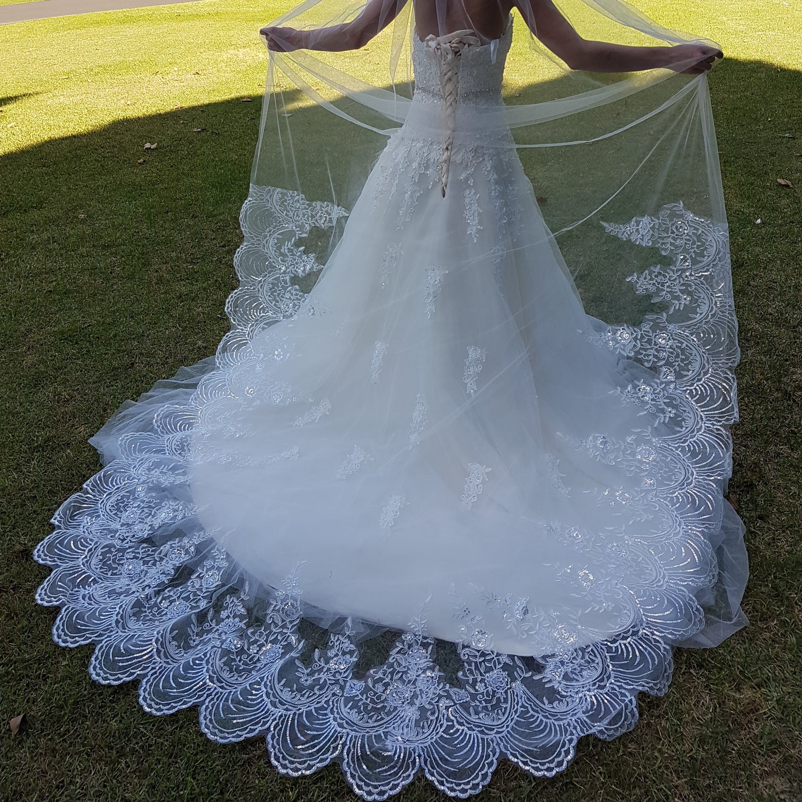 A bride in a stunning wedding gown stands on vibrant grass, capturing a moment of happiness and celebration.