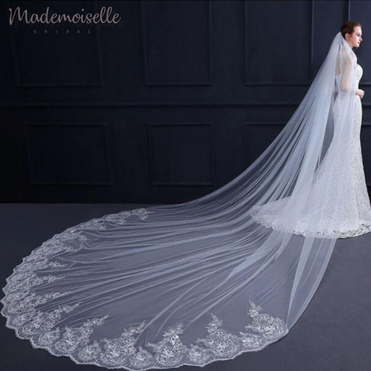 The bride showcases a stunning long lace veil, enhancing her beauty and sophistication during the ceremony.