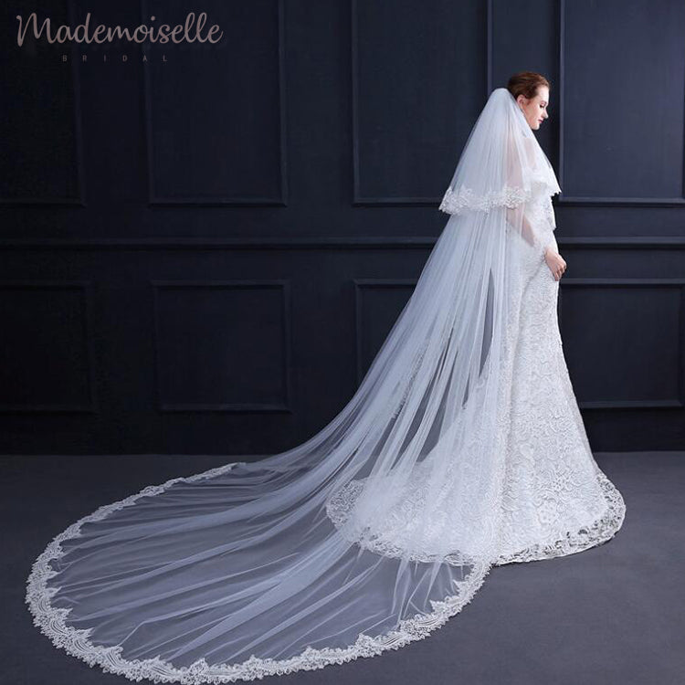 The bride showcases a beautiful long veil with intricate lace trim, adding a touch of grace to her wedding look.