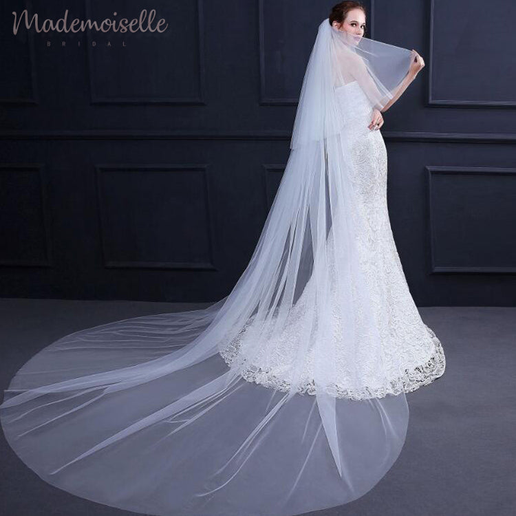 A beautiful bride dons a long veil with exquisite white lace trim, enhancing her bridal elegance and charm.