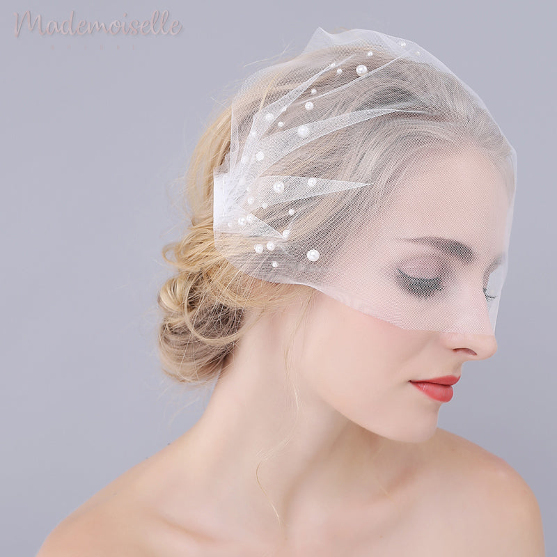 Front view of model wearing a white birdcage wedding veil with pearl beads