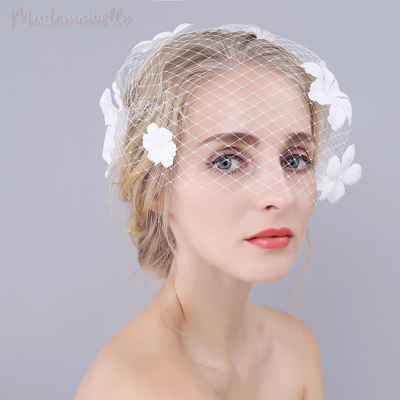 Side view of model wearing a white birdcage wedding veil with white flowers