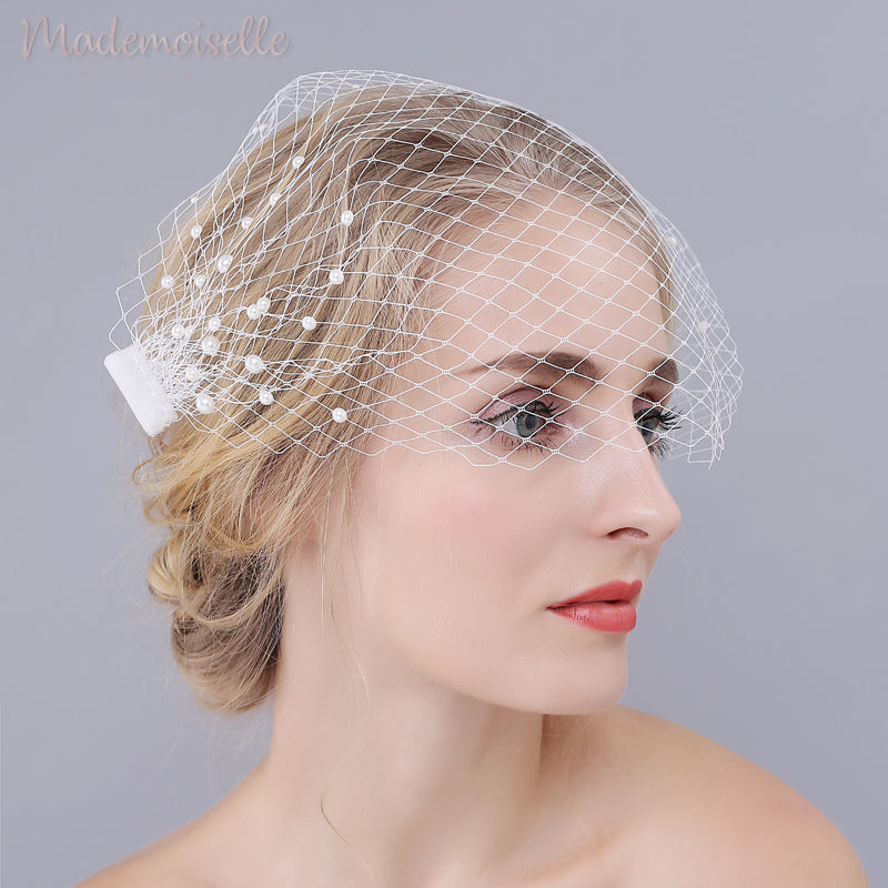 A side view of model wearing a white netted birdcage wedding veil with pearl beads