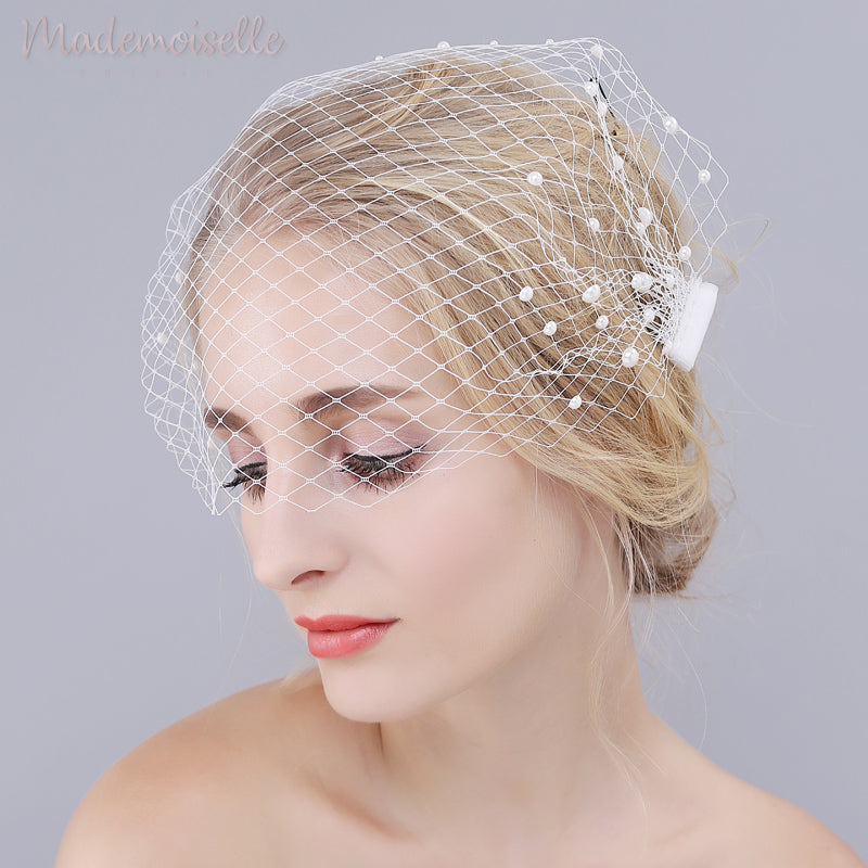 Model wearing white netted birdcage wedding veil with pearl beads