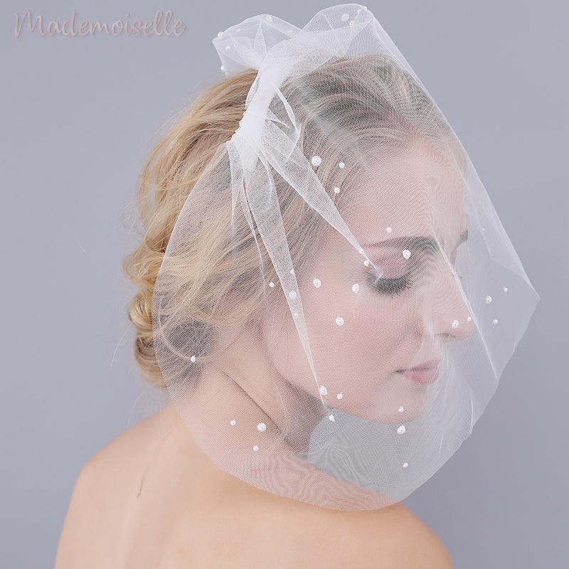Model wearing a white birdcage wedding veil with pearl beads