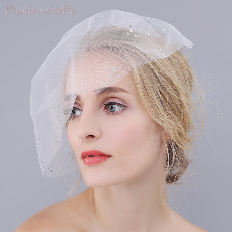 Front view of model wearing a white birdcage wedding veil with rhinestones